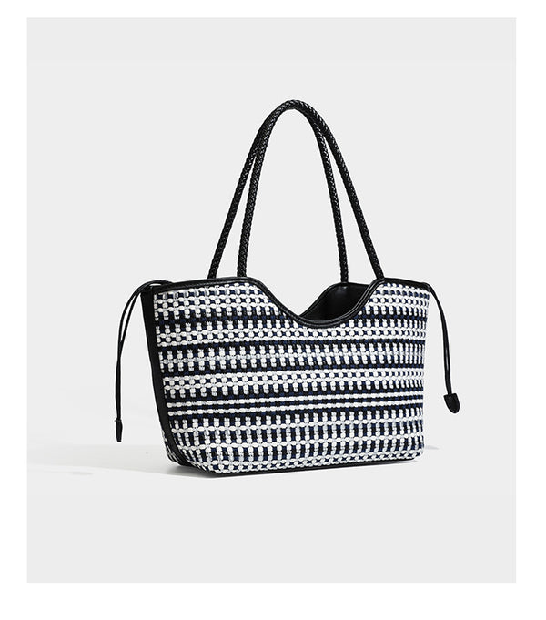Large woven checker-pattern tote bag with dark braided shoulder straps, leather-look trim, and drawstring side ties, detail