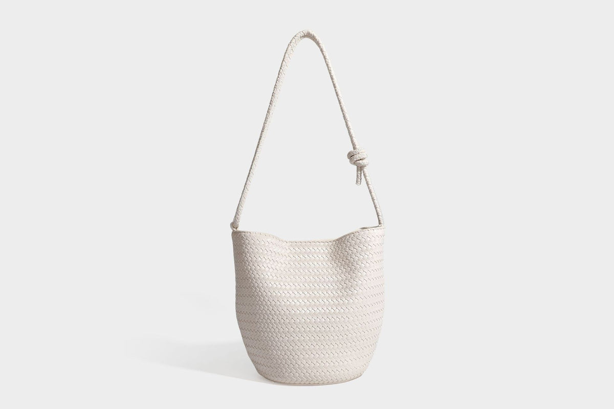 Olive green woven leather-look bucket bag with braided crossbody strap, knotted adjustment, and gold-tone tassel charm with