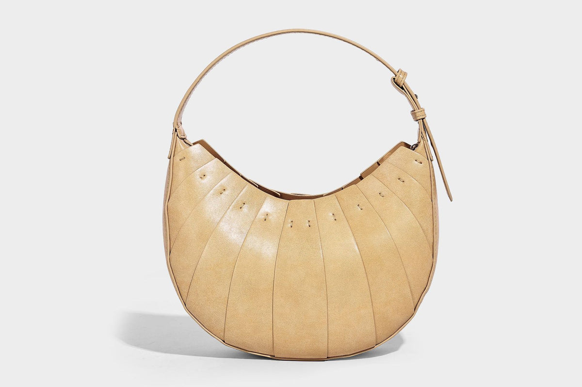 Crescent half-moon shoulder bag with vertical panel seaming, matte-satin leather-look finish, and adjustable gold-tone