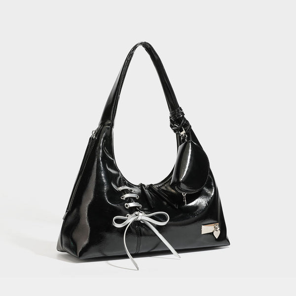 Weich fallende Hobo-Schultertasche mit glänzender Oberfläche in Lederoptik, silberfarbenen Schnürringösen und Schleife aus Ripsband auf der Vorderseite, Detail