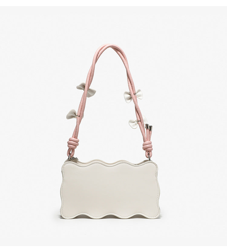 Small structured scalloped-edge shoulder bag with bow-tied pink cord strap and silver heart charm pendant, detail view 12