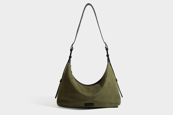 Slouchy olive green canvas hobo shoulder bag with black leather-look trim, zip-top closure, and adjustable strap, detail view