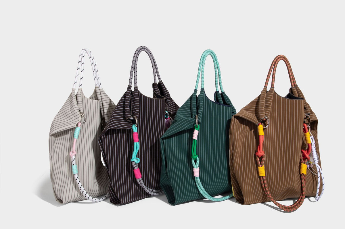 Slouchy pinstripe tote bag with braided rope handles, metal ring hardware, and colorful knotted rope charm, detail view 39