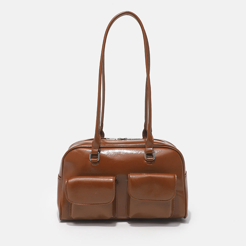 Structured glossy leather-look bowling shoulder bag with two front flap pockets, top zip closure, and long double shoulder