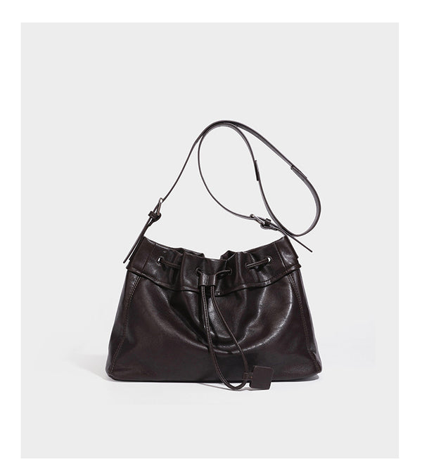 Slouchy drawstring bucket bag in dark brown leather-look finish with long adjustable shoulder strap and gathered tie closure