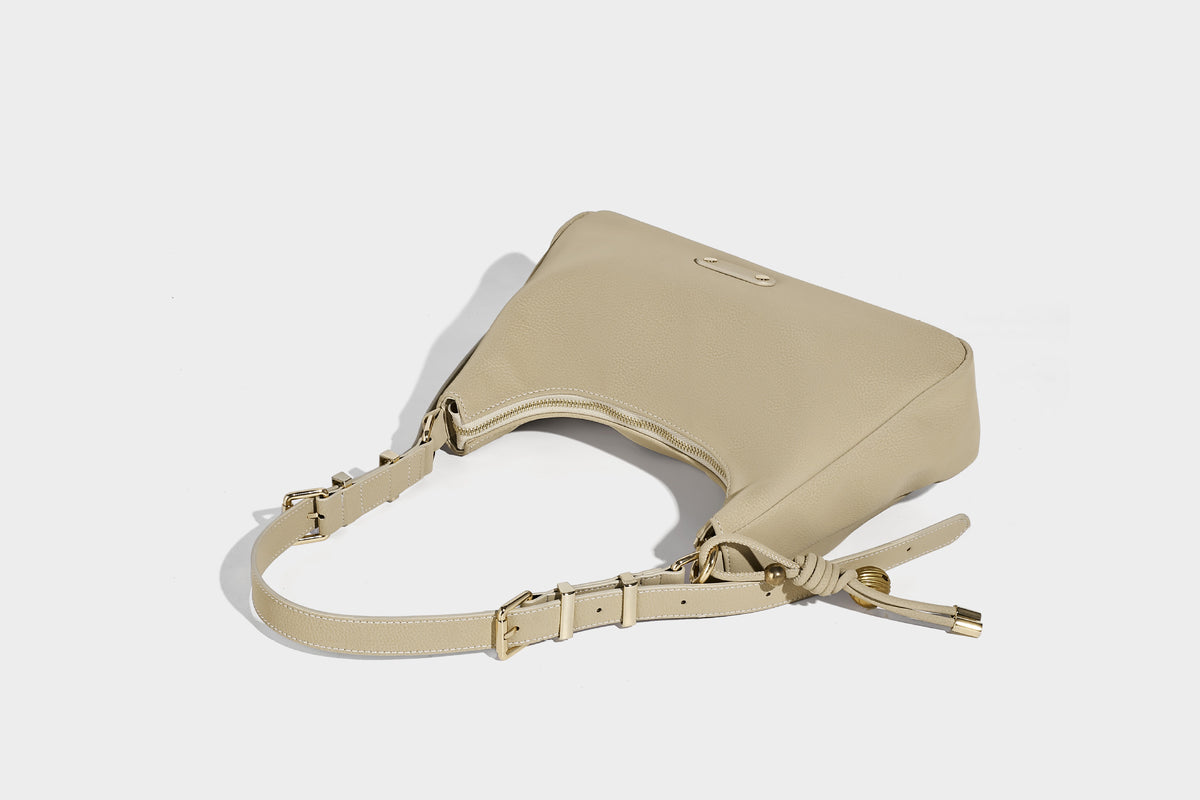 Crescent hobo shoulder bag in pebbled leather-look finish with top zipper, adjustable strap, gold-tone ring hardware, and