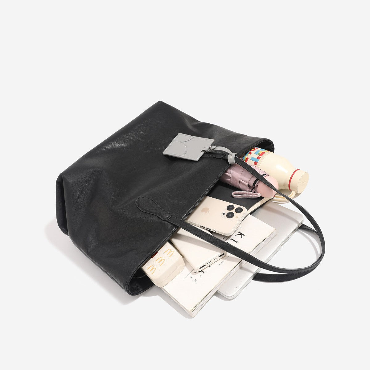 Oversized slouchy leather-look tote bag with long shoulder straps, contrast grey hanging tag, and silver-tone hardware
