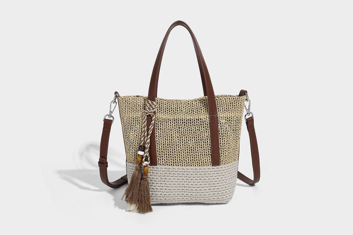 Two-tone open-weave tote bag in beige and cream with brown leather-look handles, tassel bead charm, and detachable