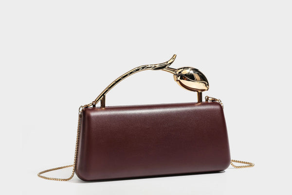 Strukturierte rechteckige Clutch mit goldfarbenem Henkel in Form einer Rosenknospe und abnehmbarem Kettenriemen in Metallic-Optik, Detailansicht