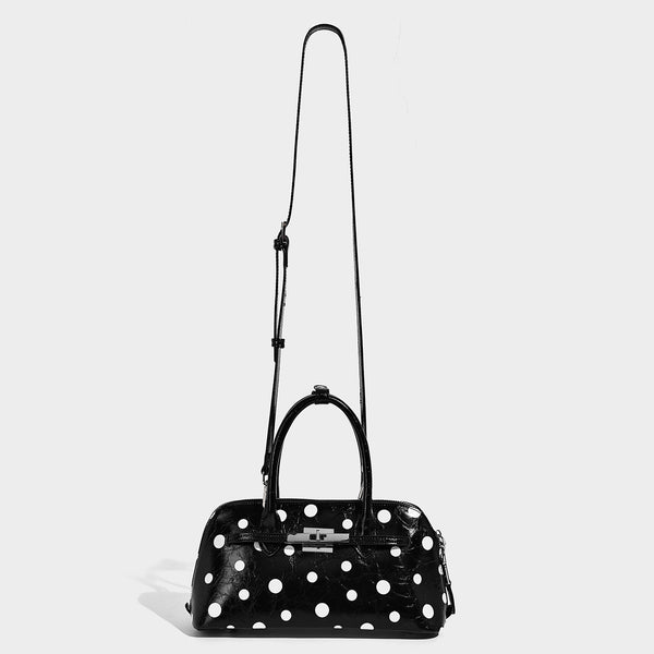 Glossy structured polka-dot satchel bag with dual top handles, silver turn-lock hardware, and detachable shoulder strap
