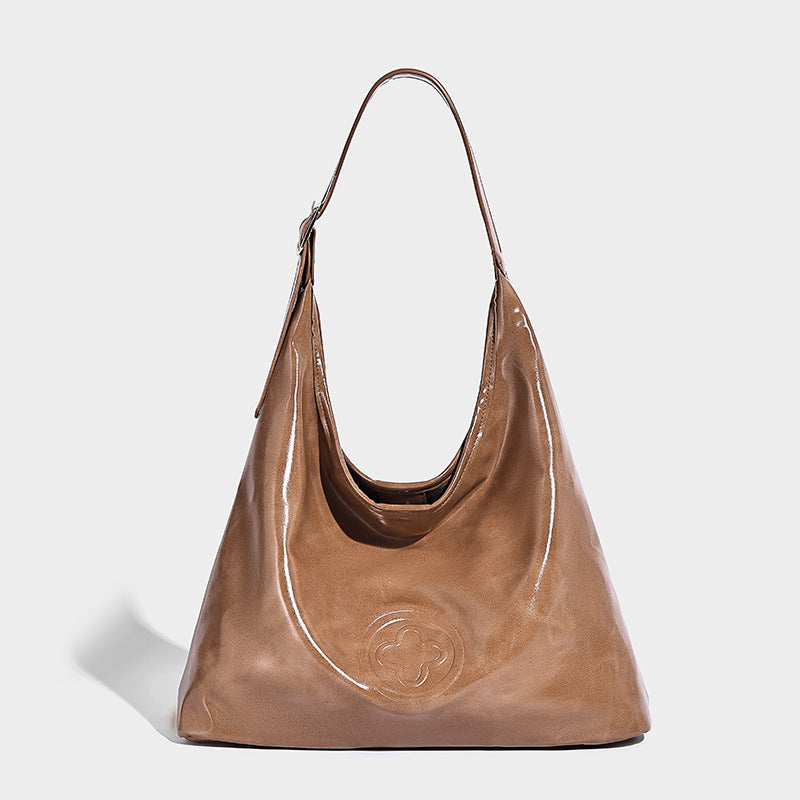 Glossy slouchy hobo shoulder bag with adjustable strap and embossed floral emblem, detail view 3