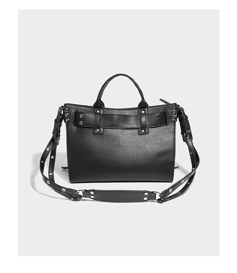 Black structured rectangular satchel bag with silver-tone rivets, large front buckle strap, zip pockets, dual top handles