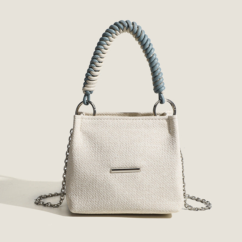 Small structured trapezoid mini bag with coiled rope top handle and silver-tone chain strap in textured fabric, detail view 7