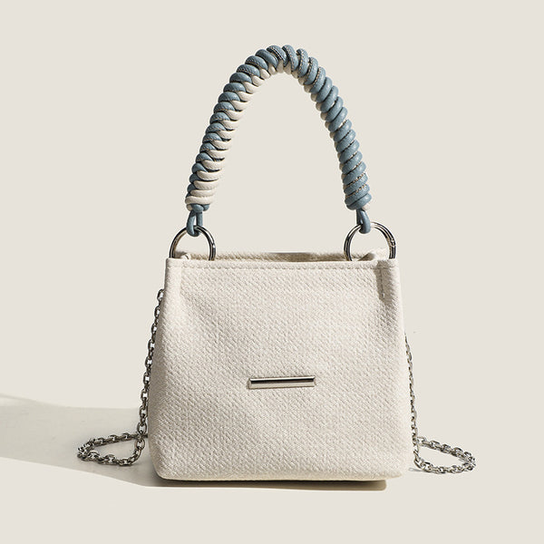 Small structured trapezoid mini bag with coiled rope top handle and silver-tone chain strap in textured fabric, detail view 7