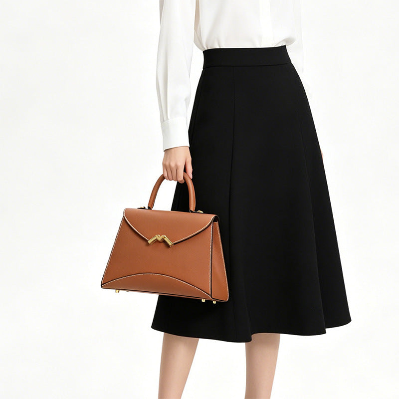 Structured trapezoid top-handle satchel in golden brown cross-grain textured finish with gold M-shaped clasp hardware and