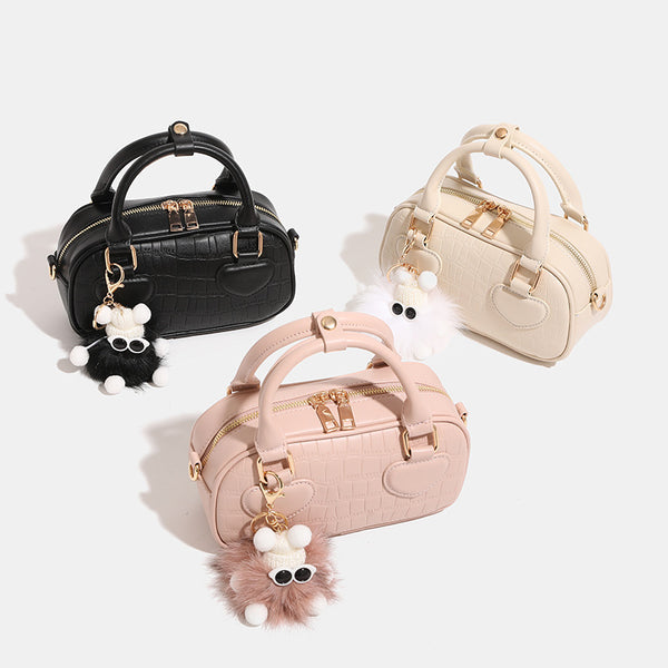 Mini croc-embossed barrel handbag with gold-tone hardware, dual zip top handles, detachable crossbody strap, and fluffy