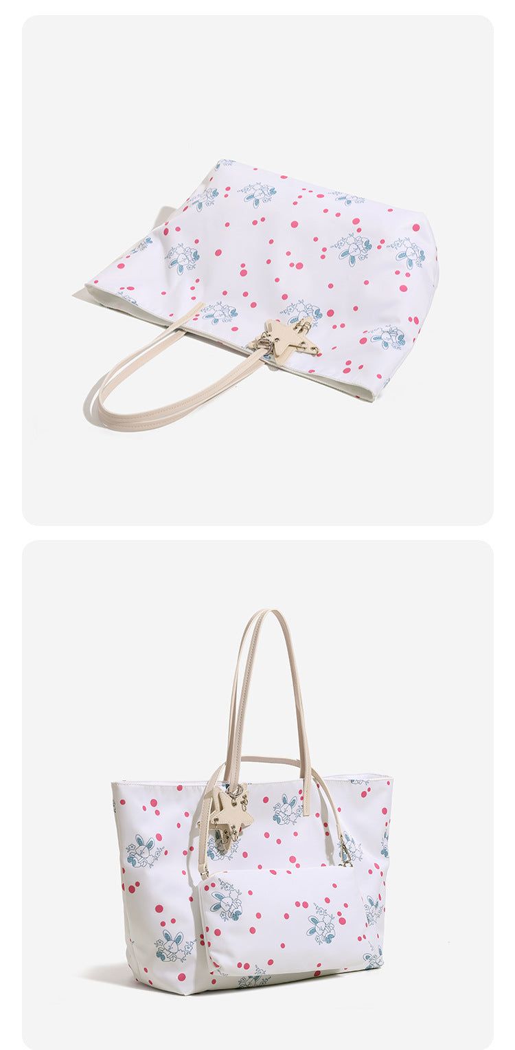 Large reversible floral print tote bag with slim shoulder straps, star charm hardware, and matching zip pouch, detail view 9