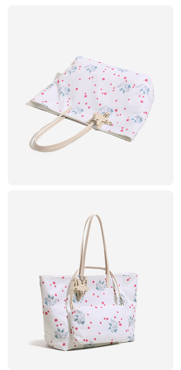 Large reversible floral print tote bag with slim shoulder straps, star charm hardware, and matching zip pouch, detail view 9
