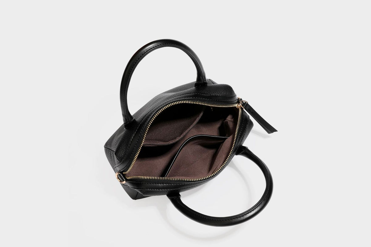 Small structured pillow satchel bag with pebbled leather-look finish, dual rolled top handles, gold-tone gourd emblem, and