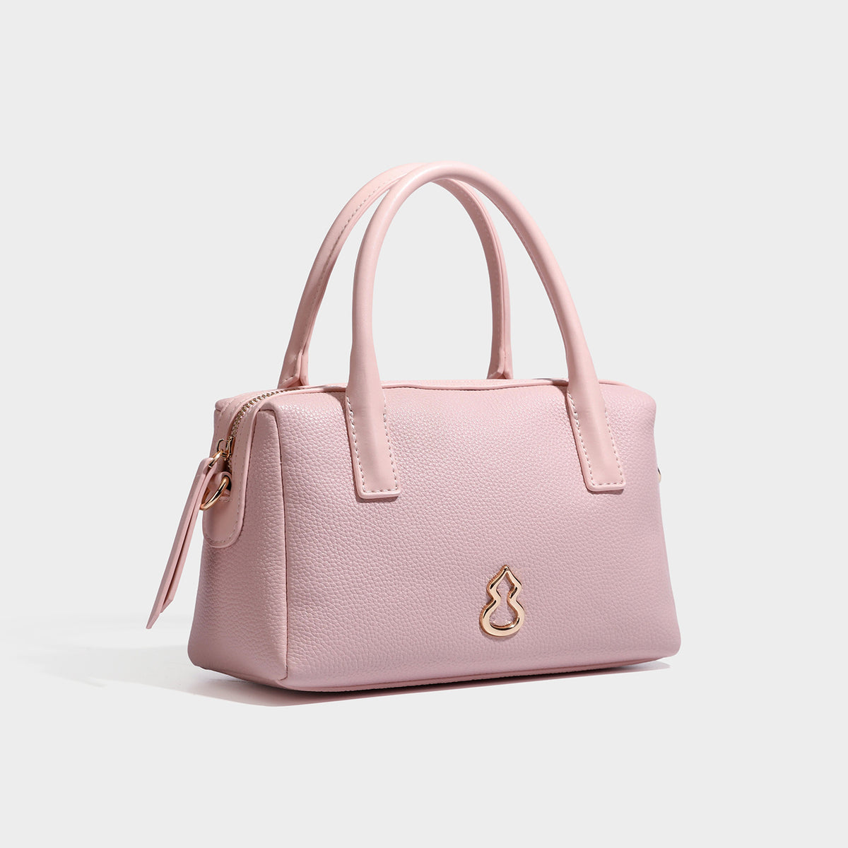 Small structured pillow satchel bag with pebbled leather-look finish, dual rolled top handles, gold-tone gourd emblem, and
