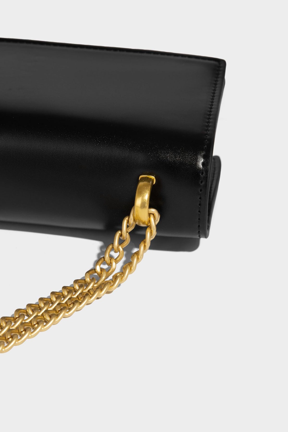 Structured rectangular crossbody bag with glossy finish, three vertical gold-tone embossed plaques, and gold chain strap