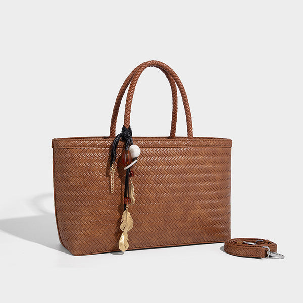 Structured woven-texture tote bag with brown braided top handles, decorative tassel charm, and detachable shoulder strap
