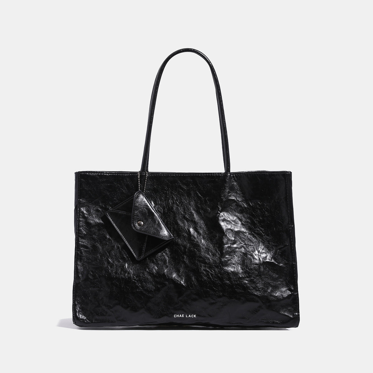 Structured rectangular crinkle leather-look tote bag with long rounded handles, zip top, and envelope-style hanging tag