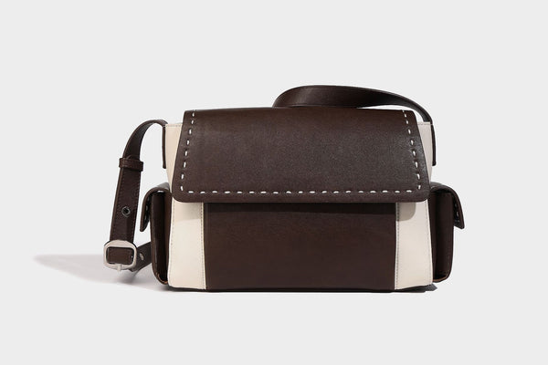 Structured flap crossbody bag in dark brown and cream color-block with white contrast stitching, adjustable shoulder strap