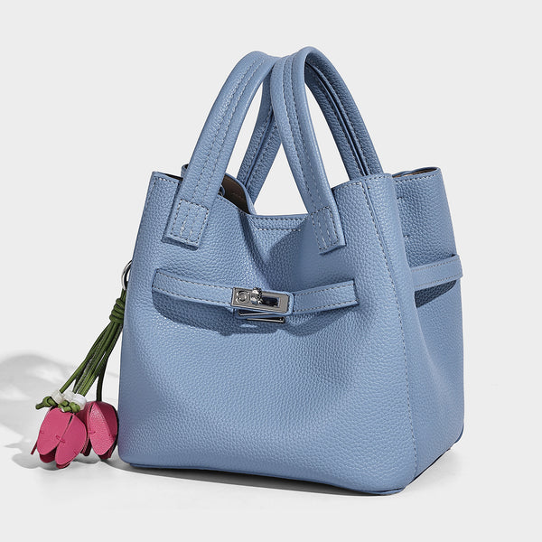 Small structured pebbled bucket tote bag with dual top handles, silver turn-lock front pocket, and detachable shoulder strap