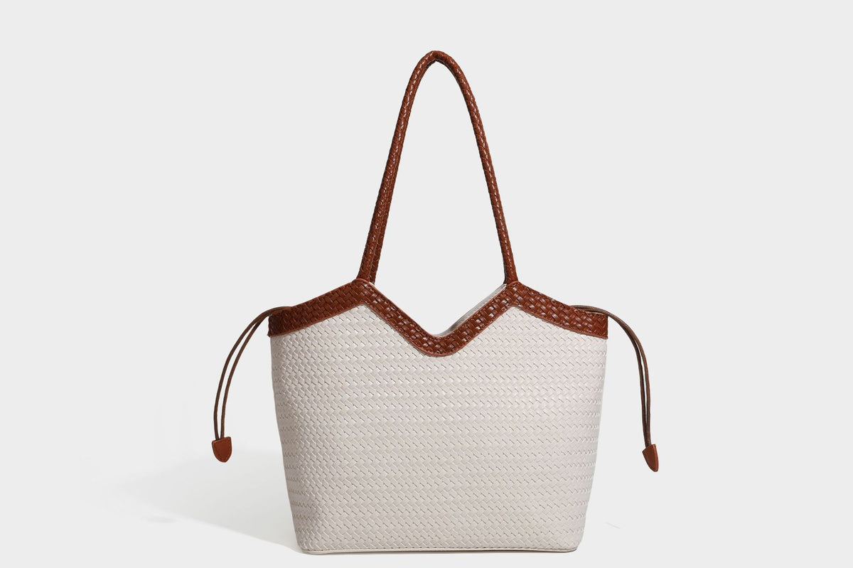 Olivgrüne Tote-Bag in Korbgeflecht-Optik mit dunkelbraunen geflochtenen Schulterriemen, seitlichen Kordelzügen und Perlenanhänger in Goldoptik