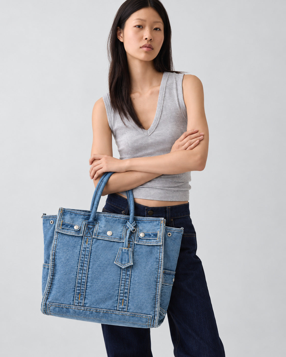 Large washed denim patchwork tote bag with snap-flap front pockets, rolled handles, and detachable shoulder strap, detail