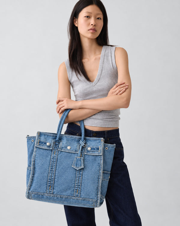Large washed denim patchwork tote bag with snap-flap front pockets, rolled handles, and detachable shoulder strap, detail