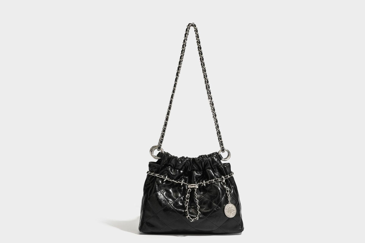 Glossy diamond-quilted drawstring bucket bag with silver chain shoulder strap and medallion charm, detail view 25