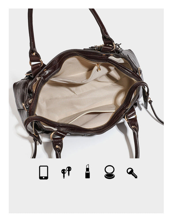 Dark brown glossy crinkled leather-look barrel bag with gold heart lock, dome studs, star charm, dual top handles and, detail