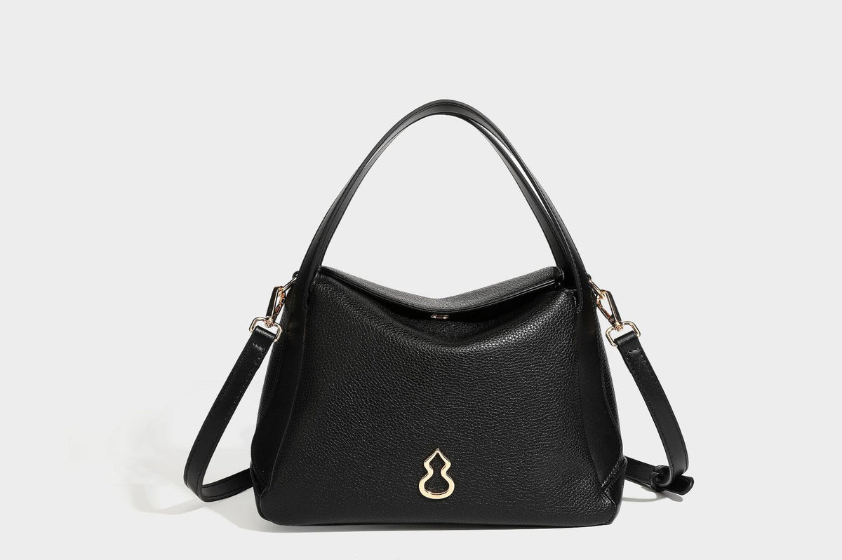 Structured pebbled leather-look shoulder bag with flap top, gold-tone emblem hardware, dual top handles, and detachable