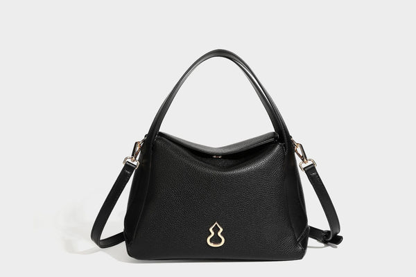 Structured pebbled leather-look shoulder bag with flap top, gold-tone emblem hardware, dual top handles, and detachable