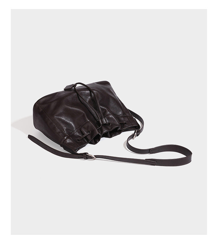 Locker fallende Beutel-Schultertasche mit Kordelzug in dunkler Espresso-Lederoptik, verstellbarem Riemen und Metallringbeschlägen