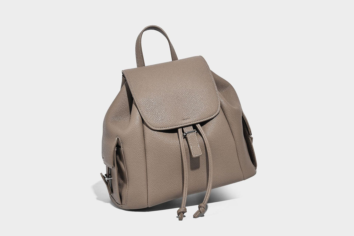 Compact pebbled leather-look flap drawstring backpack handbag with side pockets, top handle, and silver-tone hardware, detail