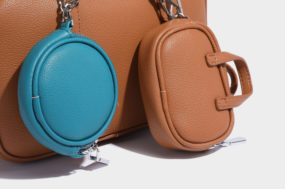 Structured pebbled leather-look Boston bowling bag in tan with blue detachable round mini pouch, dual top handles, and