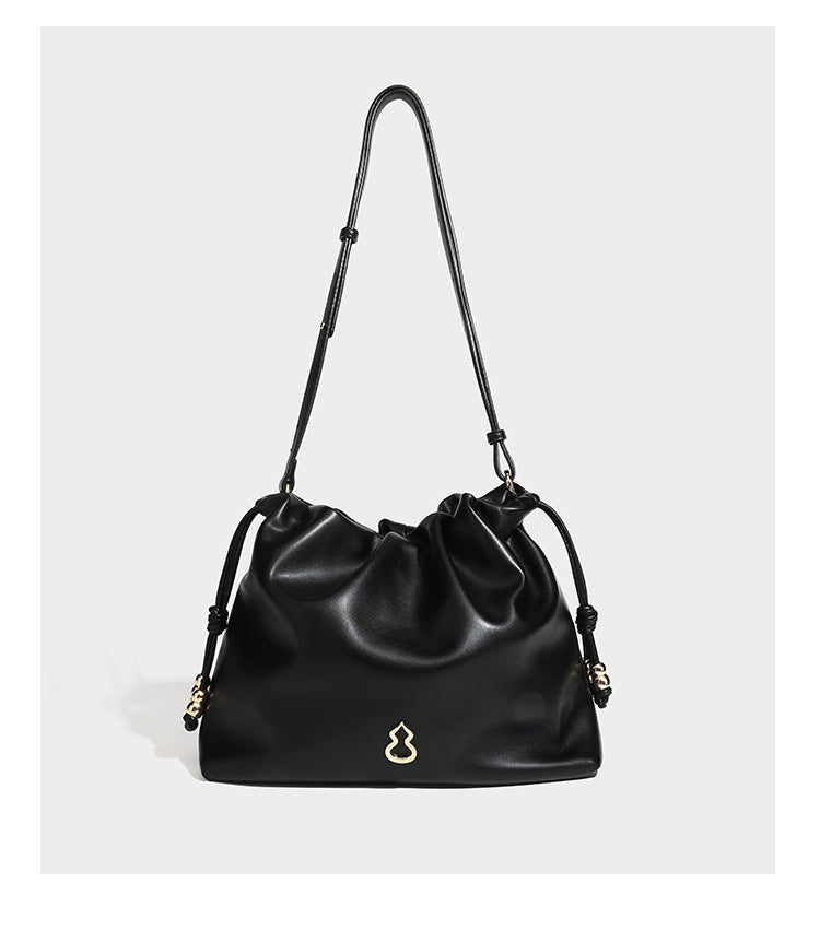 Slouchy ruched drawstring shoulder bag in smooth leather-look finish with gold-tone emblem and slim adjustable strap, detail
