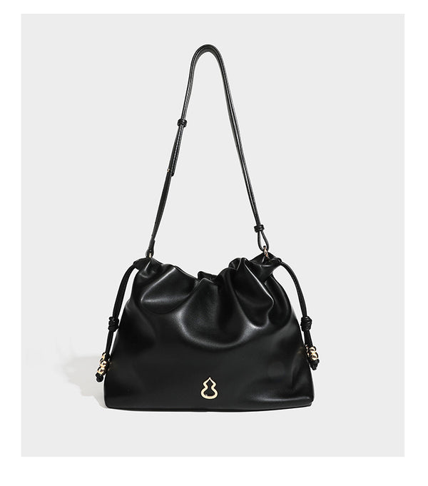 Slouchy ruched drawstring shoulder bag in smooth leather-look finish with gold-tone emblem and slim adjustable strap, detail