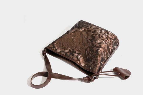 Große Hobo-Schultertasche mit Crinkle-Glanzfinish in Dunkelbraun, schmalem verstellbarem Riemen, geknoteten Beschlägen und seitlich befestigter Klappe