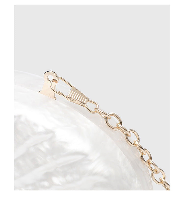 Oval pearl-finish shell clutch bag with gold-tone clasp and removable gold link chain strap, detail view 11