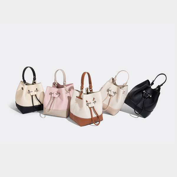 Small two-tone pebbled drawstring bucket bag with tan contrast base, metal toggle hardware, short top handle, and detachable