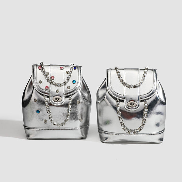 Kompakte silberfarbene Metallic-Rucksacktasche mit mehrfarbigen Kristallnieten, rundem Klappverschluss mit Drehverschluss und ineinander verflochtenem Silber