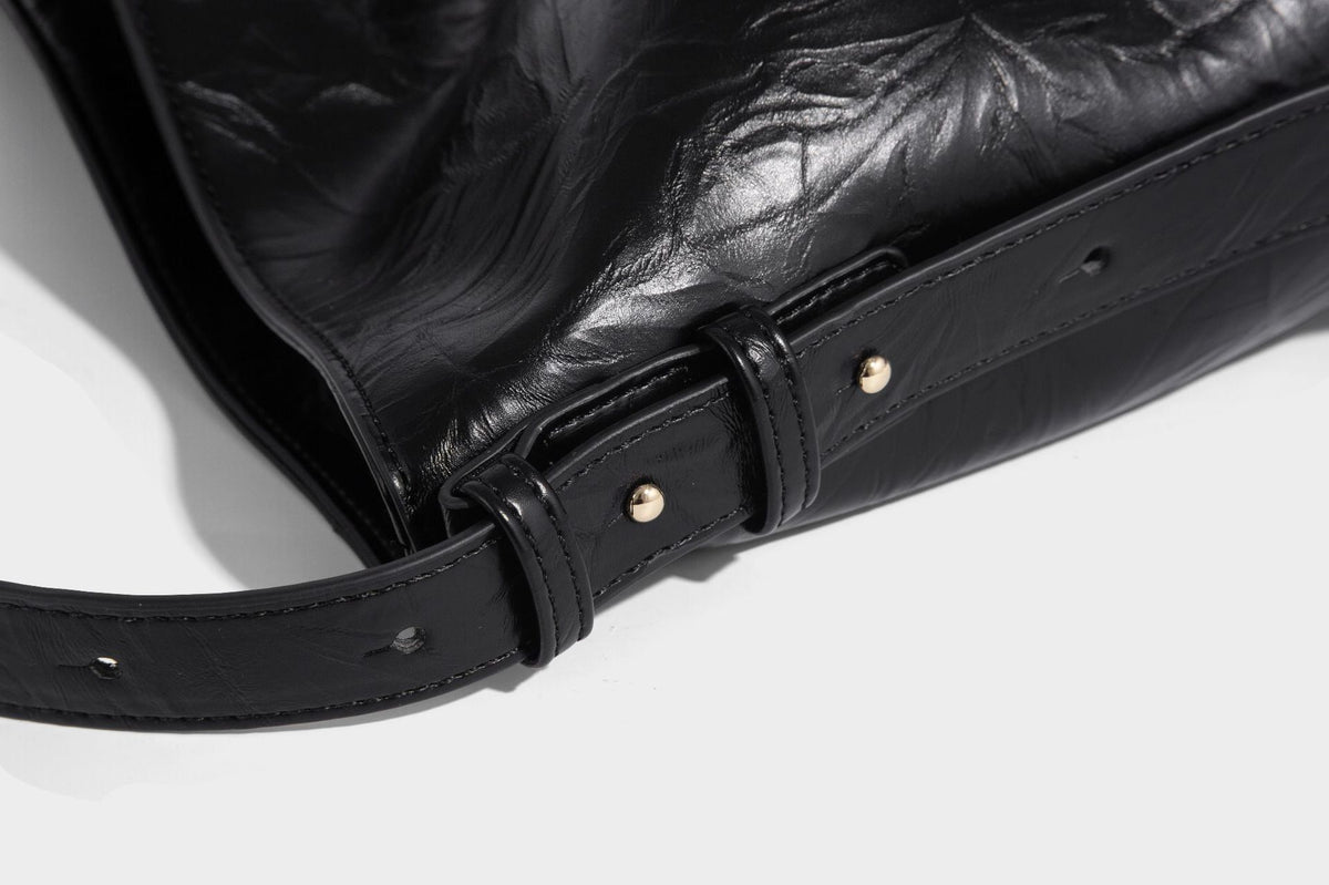 Large slouchy hobo shoulder bag in glossy crinkle leather-look finish with gold-tone emblem hardware and adjustable strap