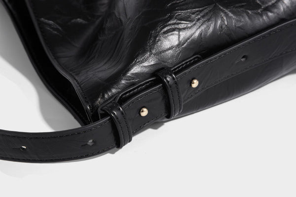 Large slouchy hobo shoulder bag in glossy crinkle leather-look finish with gold-tone emblem hardware and adjustable strap