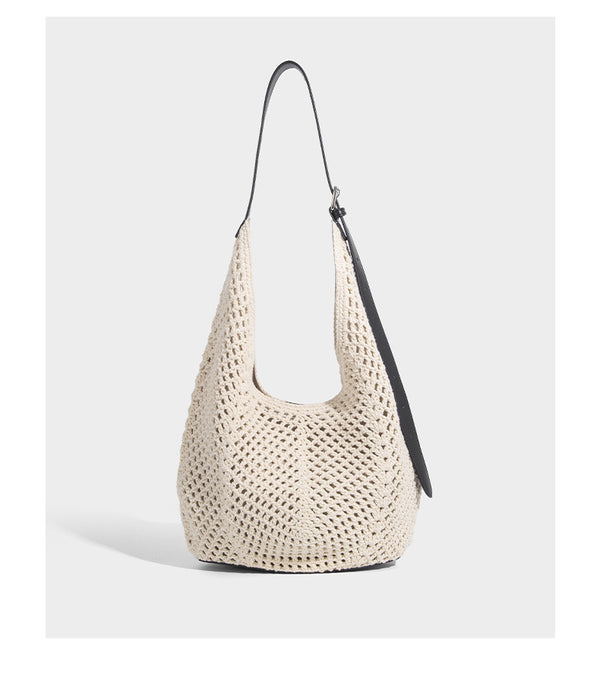 Cream openwork crochet hobo bag with black leather-look strap and trim patch accent, slouchy teardrop silhouette, detail view