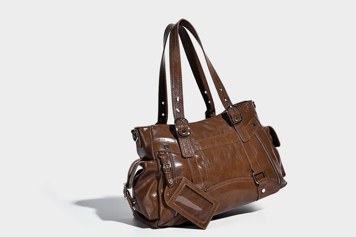 Glossy structured black tote shoulder bag with silver buckle hardware, zip pockets, dual top handles, and detachable, detail