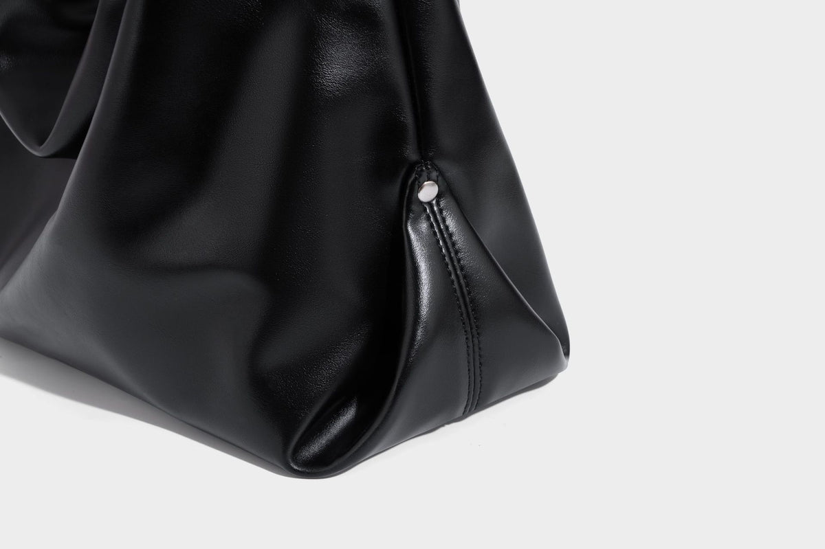 Große schwarze, glänzende Hobo-Schultertasche in Lederoptik mit mit Ösen besetztem Riemen, silberfarbenen Beschlägen und abnehmbarem